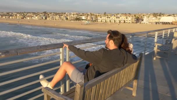 Para w Hermosa Beach Pier słynnej sceny La Land, podziwiając piękny widok na ocean z rozbłyskiem słońca — Wideo stockowe