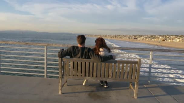 Para mężczyzn i kobiet w Hermosa Beach Pier słynnej sceny La Land, podziwiając piękny widok na ocean z rozbłyskiem słońca — Wideo stockowe