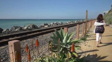 Yaşlı olgun bir kadın, tren yolunun yakınında mutlu bir şekilde yürüyor. Güzel pasifik sahili, Orange County, San Clemente.