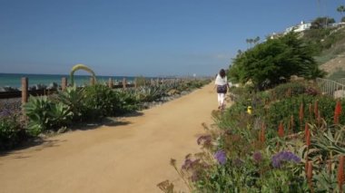 Yaşlı olgun bir kadın, tren yolunun yakınında mutlu bir şekilde yürüyor. Güzel pasifik sahili, Orange County, San Clemente.