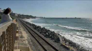 Meşhur tren yolunda dalgaları seyreden olgun bir kadın. Güzel pasifik sahili, Orange County, San Clemente.