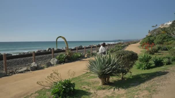 Mujer madura mayor caminando feliz en el sendero cerca de la vía férrea hermoso paisaje costa pacífica Condado de Orange San Clemente — Vídeos de Stock