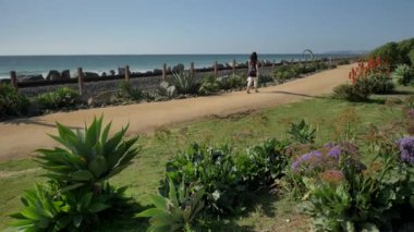 Yaşlı olgun bir kadın, tren yolunun yakınında mutlu bir şekilde yürüyor. Güzel pasifik sahili, Orange County, San Clemente.