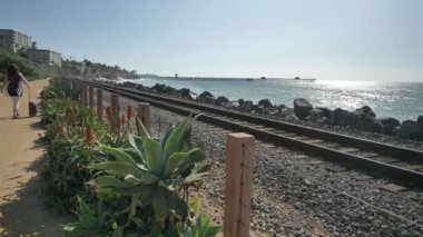 Yaşlı olgun bir kadın, tren yolunun yakınında mutlu bir şekilde yürüyor. Güzel pasifik sahili, Orange County, San Clemente.