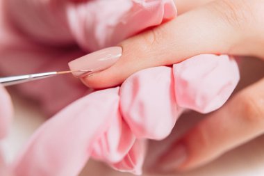 Manikür işlemi. Manikürcü oje sürüyor. Tırnak cilası..