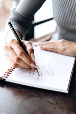 Manikürcü özel bir defterde tırnak tasarımının bir taslağını yapar..