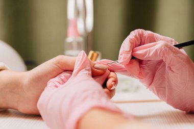 Manikür işlemi. Manikürcü oje sürüyor. Tırnak cilası..