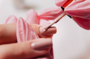 Manikür işlemi. Manikürcü oje sürüyor. Tırnak cilası..