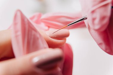 Manikür işlemi. Manikürcü oje sürüyor. Tırnak cilası..