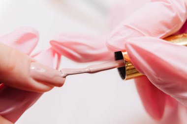 Manikür işlemi. Manikürcü oje sürüyor. Tırnak cilası..