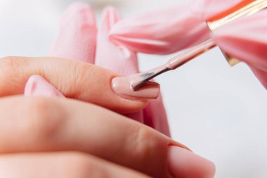 Manikür işlemi. Manikürcü oje sürüyor. Tırnak cilası..