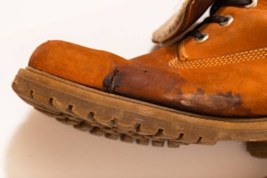 Mahvolmuş bir ayakkabı. Ayakkabının yüzeyinde çatlak ve lekeler var..