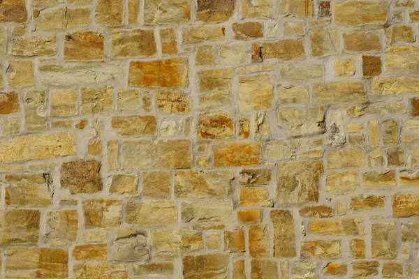 A fragment of a city wall of hewn stone on cement mortar. Stones of different sizes and colors, but in the same style.
