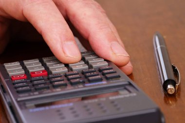 Hesap makinesine yakın çekim yap. Yanında bir kalem var..