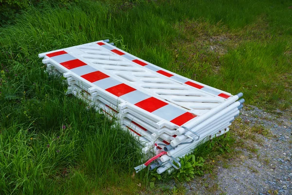 Tehlikeli bölgelerin çitle çevrilmesi için kırmızı-beyaz plastik bariyer yayalar ve çimenlerin üzerine istiflenmiş operasyon personeli için. Yakın plan..