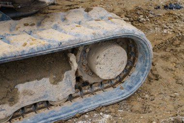 Kazıcı ya da buldozer tırtılı bir inşaat sahasında duruyor. Çelik izler kuru toprakla kaplı. Kapat..