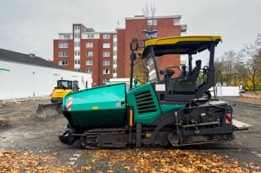 Arka planda apartmanı olan bir inşaat alanında büyük bir asfalt kaldırım.