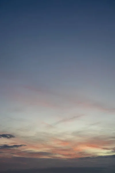 Gökyüzünün atmosferik ve renkli bir görüntüsü, koyu mavi, yumuşak mor, pembe ve turuncu ve sarı karışımlı katmanları, kopyalama alanı için barışçıl ve anlamlı bir doğal arkaplan yaratır..