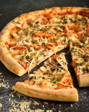 Siyah arka planda mantarlı ve domatesli pizza.