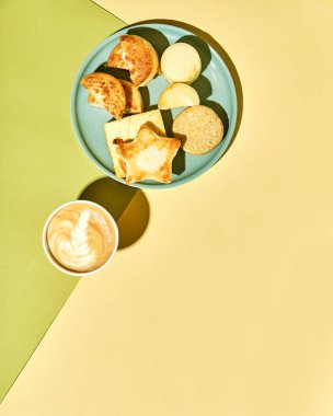 Tabakta peynirli kekler ve modern tarzda renkli bir arka planda bir fincan kahve, metin için yeri olan üst görünüm