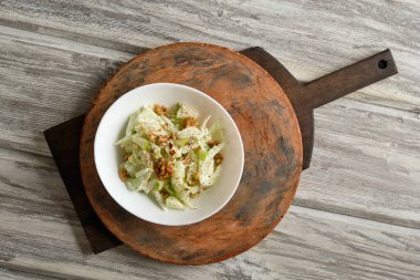 Kerevizli Waldorf salatası, hafif ahşap arka planda elmalar ve cevizler.