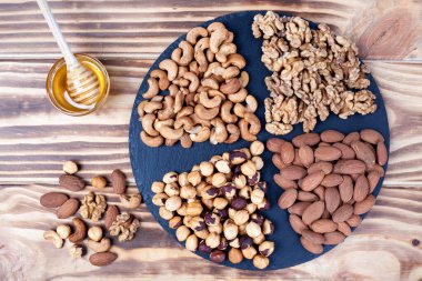 Bal kasesi ve bal sosuyla sıralanmış çeşitli fındıklar.