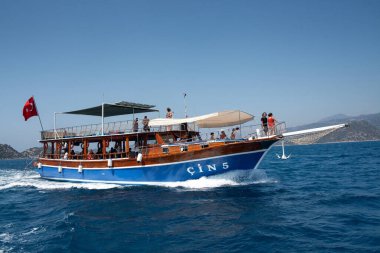 Demre, Türkiye - 07.07.2020. Denizde bir eğlence yatı. Dalgalarda Türk bayrağı taşıyan insanlarla dolu bir turist gemisi. Hızlı hareket eden gemi gemisi..