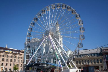 Ferris wheel on Kontraktova square in Kyiv, Ukraine. Ferris wheel with closed booths. People walking on central square.