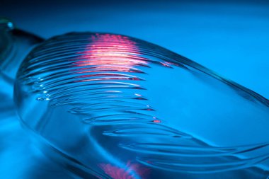 Soyut cam şişe arka planı. Dalgalı cam dokusu çok renkli ışıkla aydınlatılmış. Pembe mavi lekeler. Kapatın. Camdaki fişekler