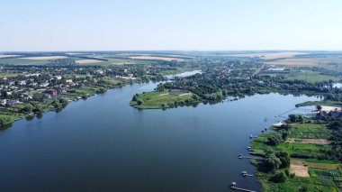Küçük köyün üzerindeki hava manzarası. Nehir kıyısındaki kırsal bölgede. Nehir kenarındaki köy. Tarlalar ve bahçeler drone görüntüsü.