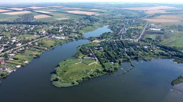 aerial view over the small village. Countryside on river coast. village by the river. fields and gardens drone view.