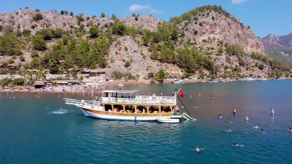 Luchtfoto van jacht in blauwe zee verankerd nabij eiland met zandkust en turquoise water. Toeristisch excursie boot schip in Turkije. — Stockfoto