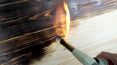 Tahtayı yakmak için bir el feneriyle ahşap bir tahta yakmak ve tahılı yaşlandırmak.