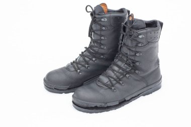 Yıpranmış tabanlı askeri tarzda botlar karla kaplı bir zeminde otururlar. Sahne, kışın soğuğunu ve ayakkabının giyimini yakalar..