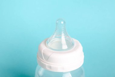 Temiz meme ucu olan bir bebek şişesinin üst kısmı. Arka plan yumuşak bir mavi, şişeye odaklı. Bebekleri beslemek için çok yaygındır..