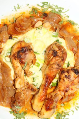 Tavuk bacağı, kasap soğanıyla pişirilmiş, patates püresi ile servis ediliyor. Yunan mutfağı, modern kaliteli baskı.