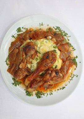 Tavuk bacağı, kasap soğanıyla pişirilmiş, patates püresi ile servis ediliyor. Yunan mutfağı, modern kaliteli baskı.