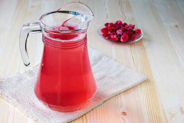 Hafif ahşap arka planda şeffaf bir sürahi içindeki böğürtlenlerden alınmış sağlıklı meyve suyu. Sağlık için besleyici bir içecek.