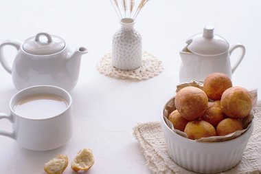 Beyaz çaydanlık, bir fincan çay ve arka planda donut olan bir kase. Kahvaltı konsepti