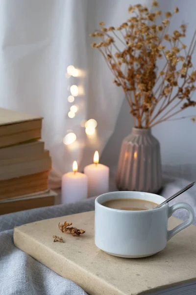 Bir fincan kahve, kitaplar, bir buket çiçek ve masada mumlar. Kahverengi-bej renkte kompozisyon. Hareketsiz yaşam, günlük yaşam konsepti.