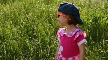 Cute little smiling girl in sunglasses in the park