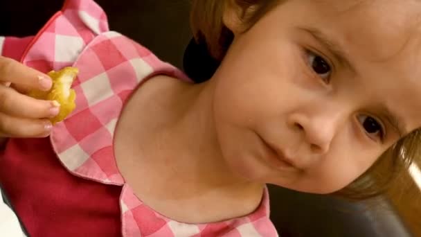 El niño está sentado en un café. Niña en vestido rojo y gorra de béisbol comiendo nuggets y papas fritas — Vídeo de stock