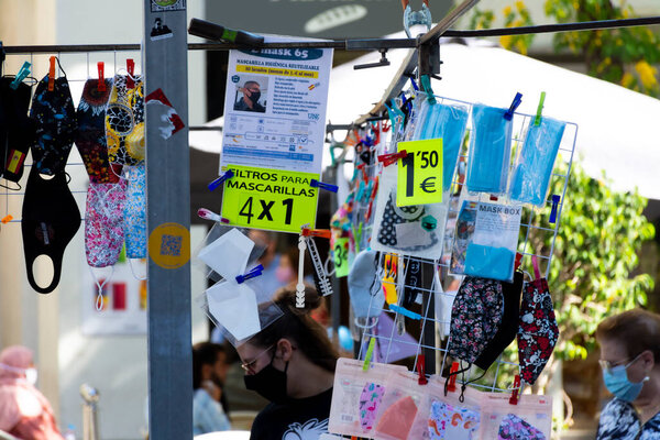 Valencia, Spain. October 11, 2020: Market stall with fashion or hygienic masks with different prints. Yellow sign: Mask filters 4 by 1 euro