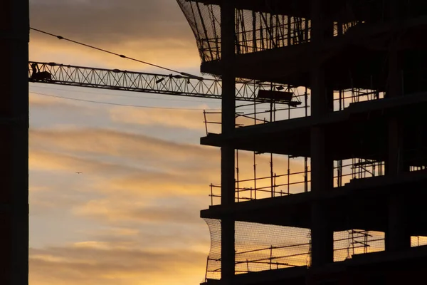 Silhouette of a building under construction with yellow clouds at sunset or sunrise