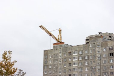 İnşaat alanında, yüksek vinçler şehirde gri bir blok ev inşa ediyor..