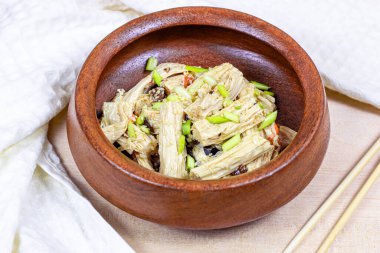 Asya tüy salatası (yuba çubukları, soya peyniri, tofu derisi) hafif arka planda yuvarlak ahşap kasede..