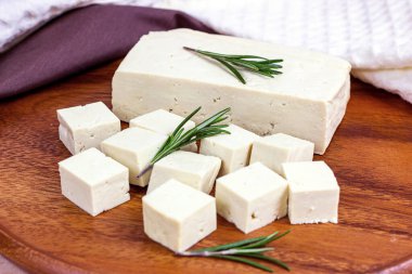 Çiğ organik vejetaryen tofu küpleri ve ahşap arka planda taze biberiye..