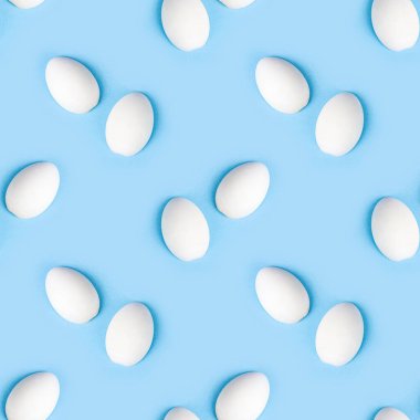 İki beyaz ahşap yumurta açık mavi arka planda kusursuz desen.