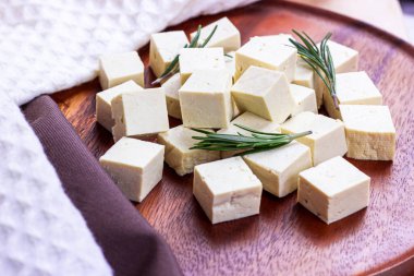 Çiğ organik vejetaryen tofu küpleri ve ahşap arka planda taze biberiye..