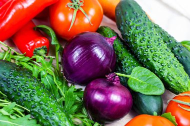 Salata için taze çiftlik sebzeleri: salatalık, domates, soğan, biber, roka yaprakları açık arkaplanda mutfakta..